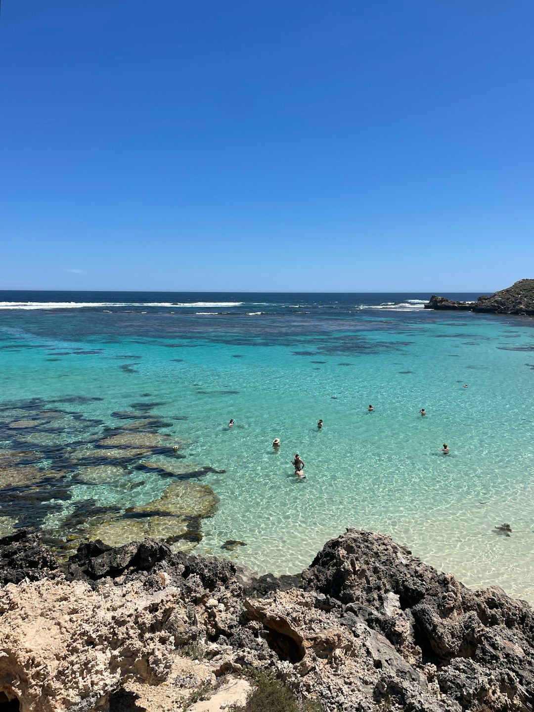 People are swimming in the clear blue water